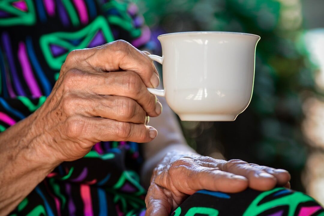 Close-up of an elderly woman's weathered hands holding a cup