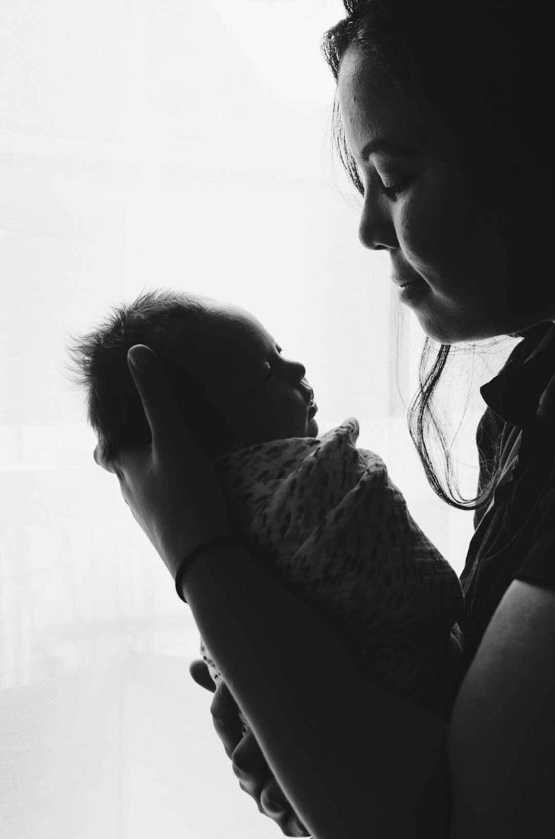 Mother holding her newborn baby by a window