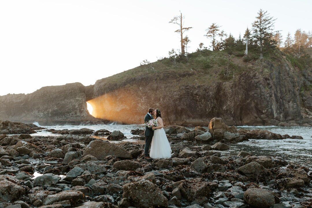 Couple embracing on a rocky beach at sunset